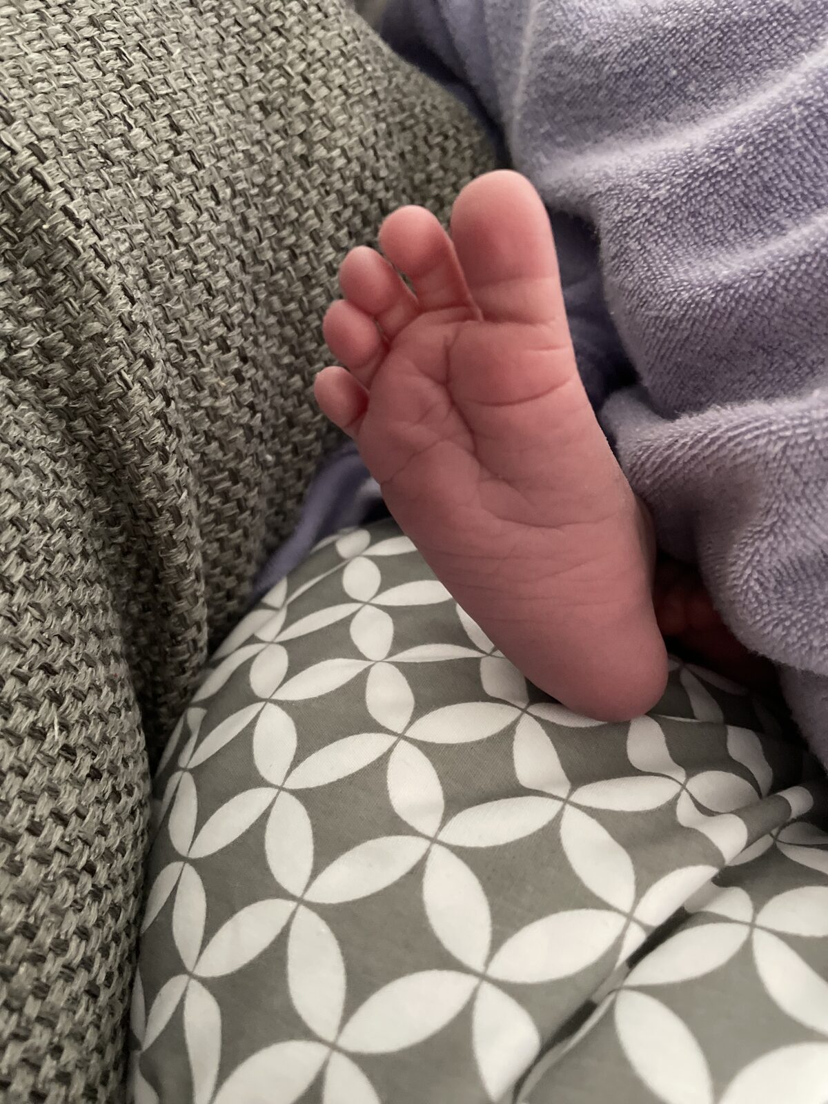 A newborn's foot beside a pillow
