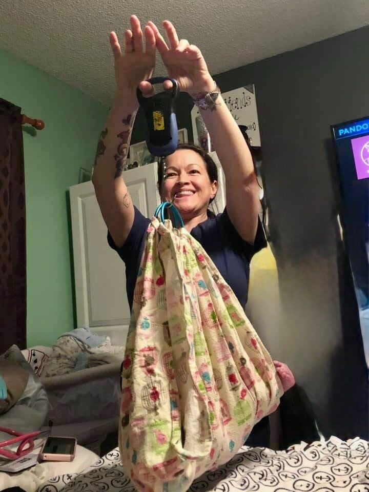 Rhonda joyfully lifting a baby in the weighing sling
